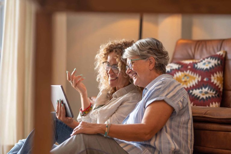 Adult daughter sitting at home with her elderly mother having a serious family conversation