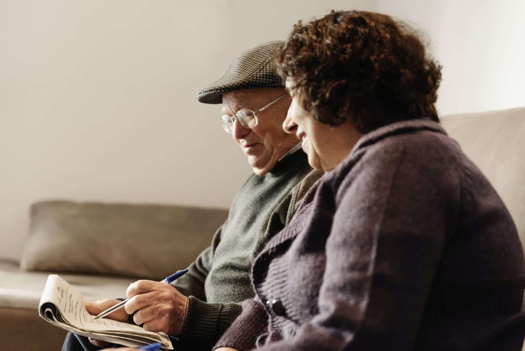 A senior couple reading a newspaper together at home
