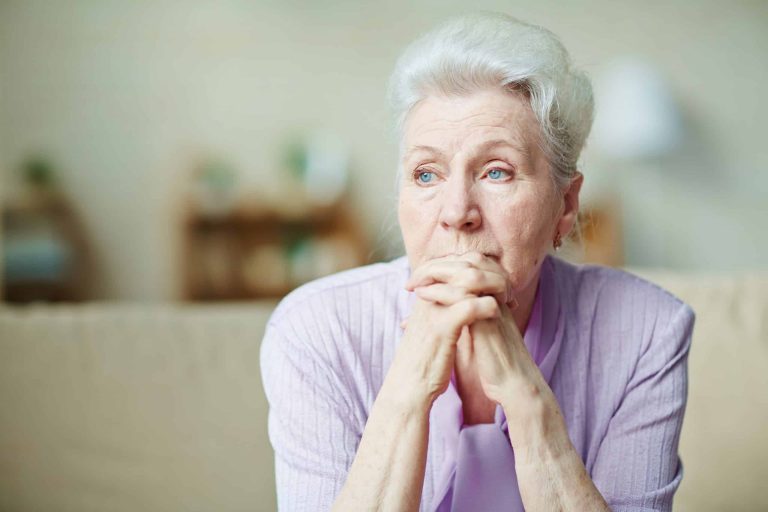 Elderly woman sitting alone with a worried expression, a sign of possible elder abuse or neglect